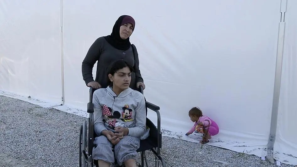 Woman with a child in a wheelchair in a refugee camp