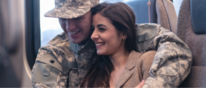 Image description: A man wearing military fatigues hugs a woman as they smile.