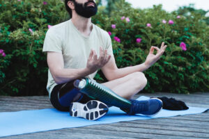 Young man with a prosthetic leg is doing meditation outdoor in a city park