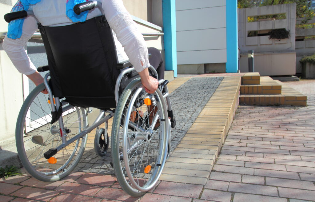 A wheelchair user uses a ramp to enter a building. 