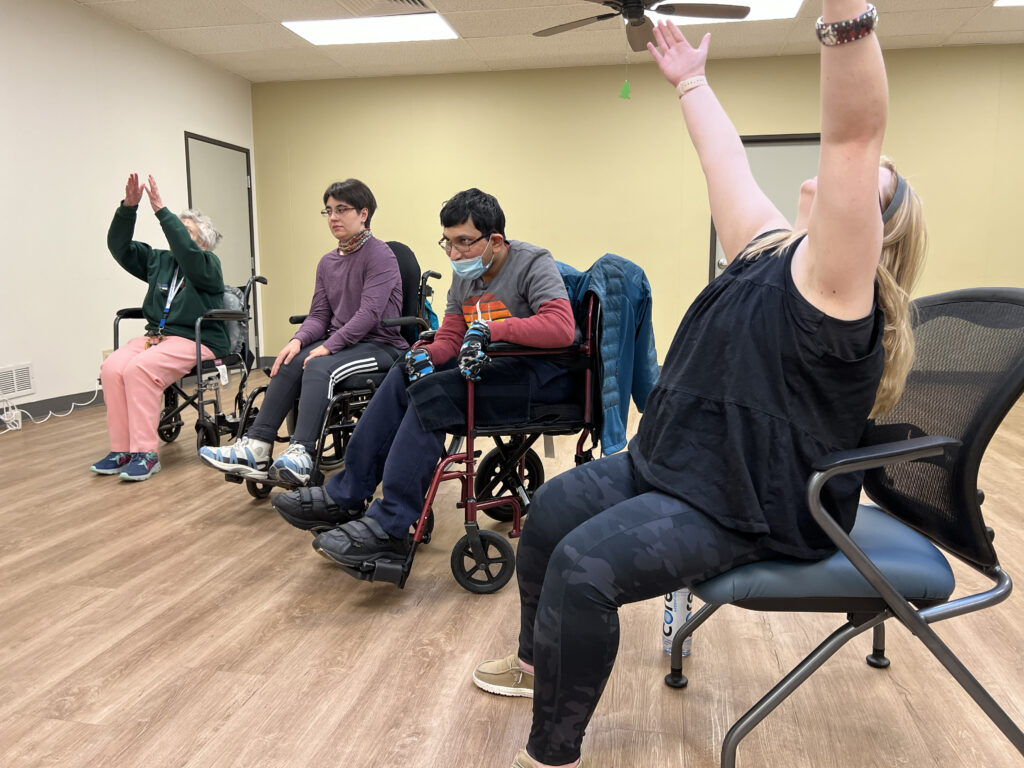 Four individuals are seen participating in CPWD's Movement and Mindfulness class. Three are wheelchair users.