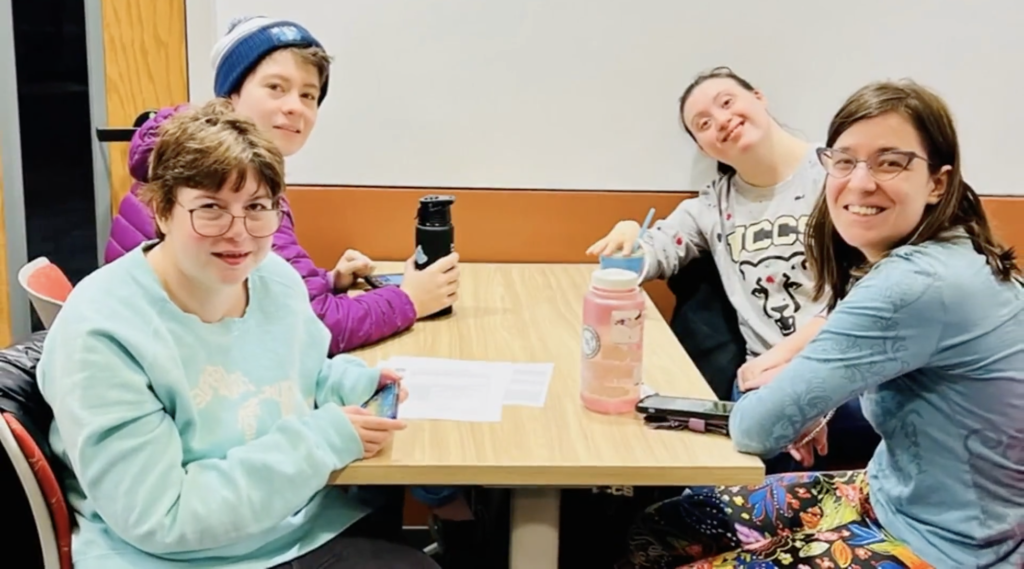 Grace Arnold is a college student with IDD. She is pictured here sitting a table with three of her friends who participate in the inclusive higher education program.